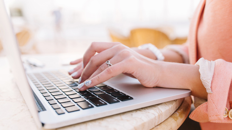 Woman typing on laptop silver nail polish