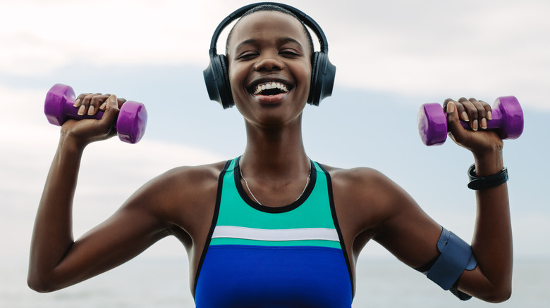 woman with headphones lifting dumbbells