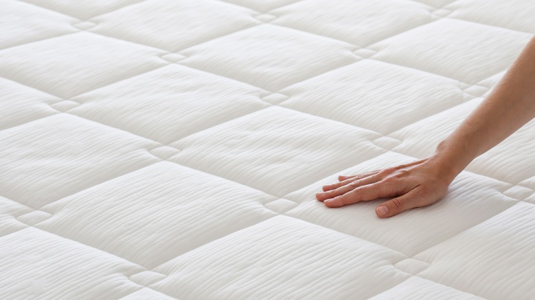 person feeling firmness of mattress