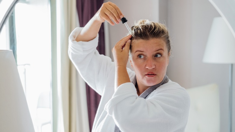 Woman applies oil to scalp