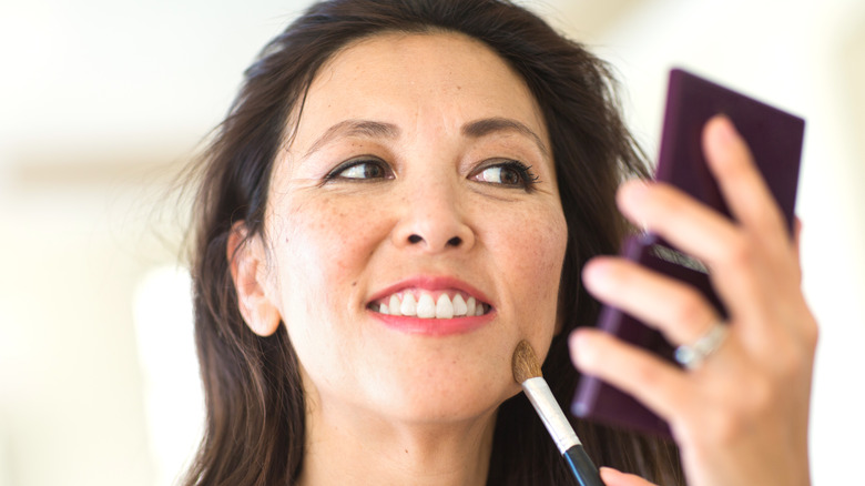 Woman smiling and applying makeup 