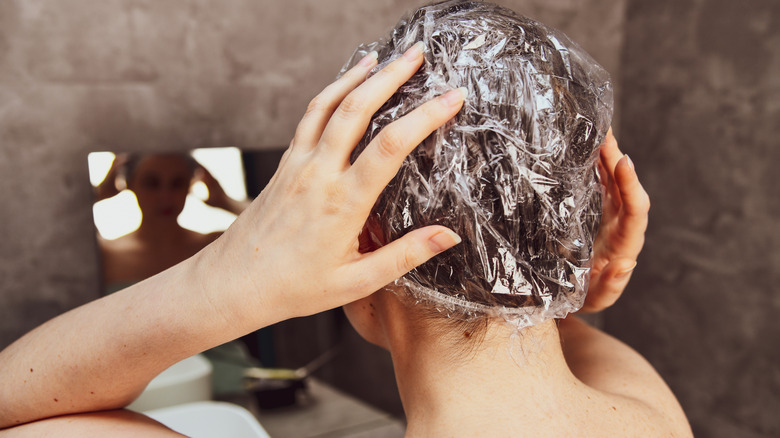 Woman covers processing hair with shower cap