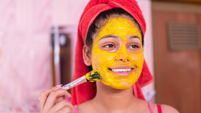 Woman painting on yellow face mask