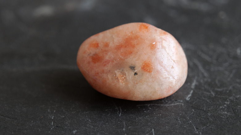 Tumbled sunstone on grey background