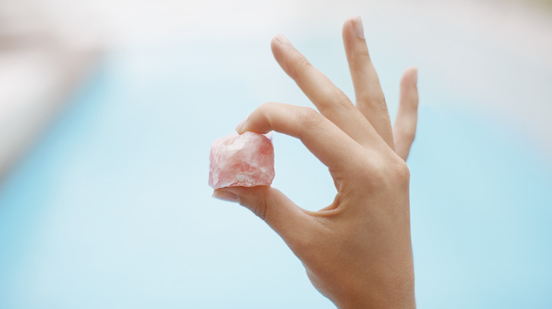 hand holding rose quartz on blue background