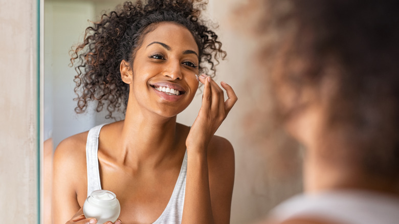 woman applying moisturizer to face