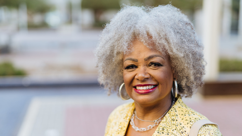 A woman with silvery natural hair smiles at the camera.