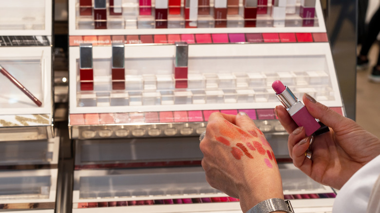 A woman testing out lipsticks at a store.