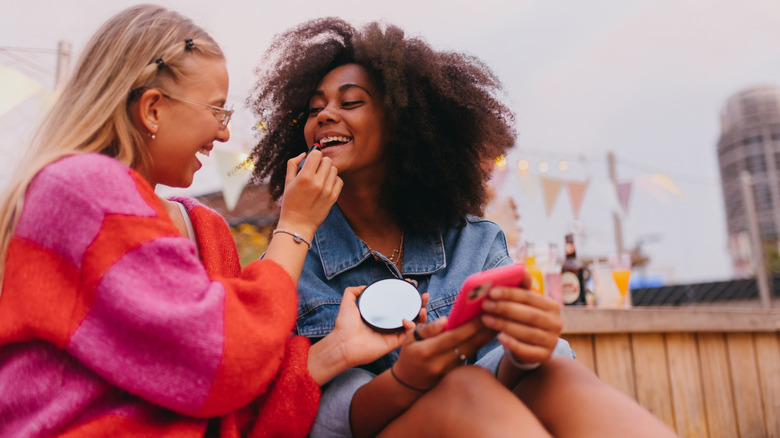 Two friends doing each other's makeup.