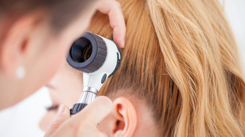 doctor using dermatoscope on scalp