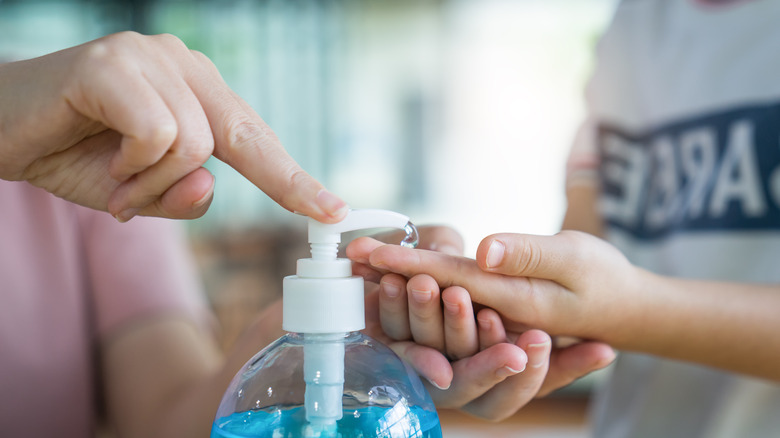 Adult helping child with sanitizer