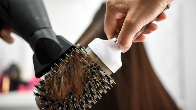 hairdresser using hair dryer and round brush