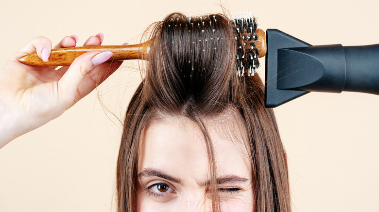 woman using round brush and hair dryer