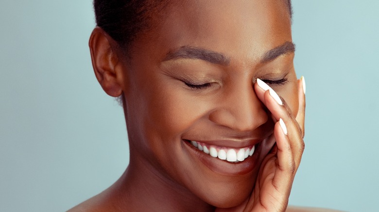 Smiling Black woman touching face