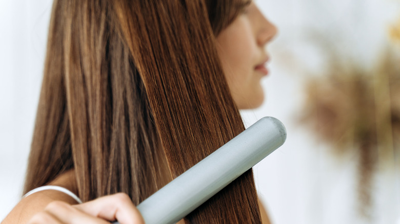 A woman straightening her hair