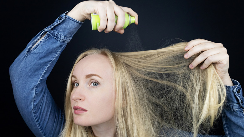 A woman applying dry shampoo