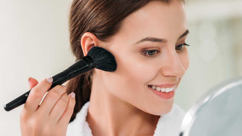 woman applying bronzer to face