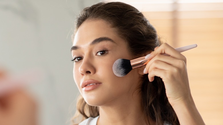 woman applying bronzer to face