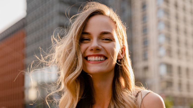 A smiling woman with a square face shape and side parted hair.