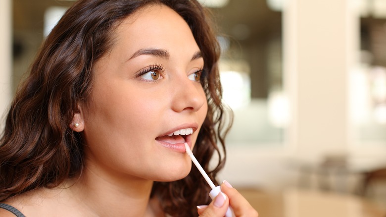 Woman applies hydrating lip oil