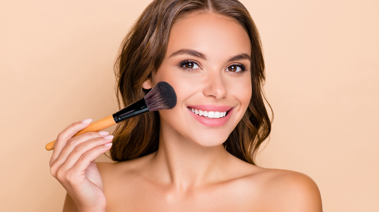 Woman applying makeup with a brush