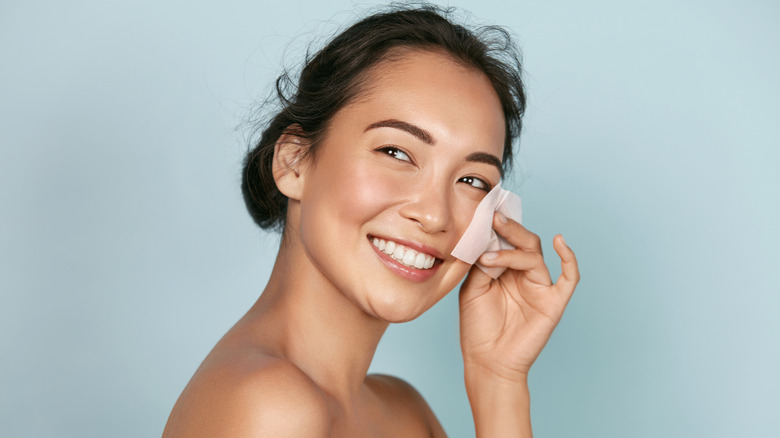 Woman using blotting paper on her face