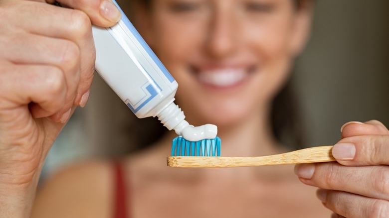 Woman applying toothpaste to toothbrush