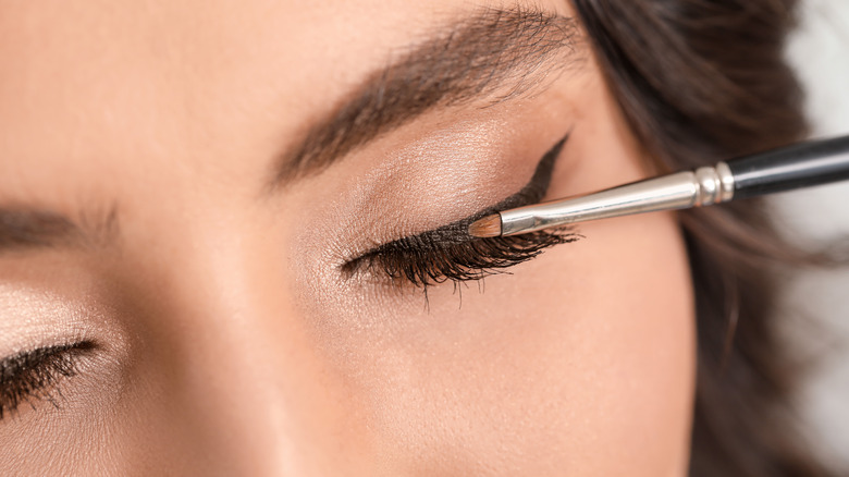 woman applying cat-eye makeup