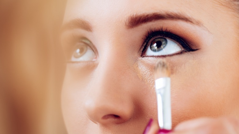 Woman applying concealer under her eye