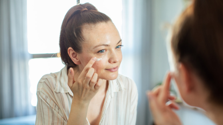 Woman applying eye cream in morning