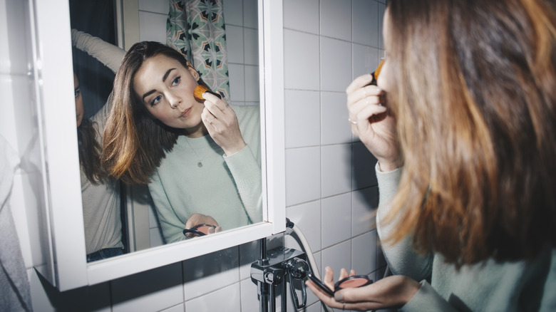 A woman applying powder blush