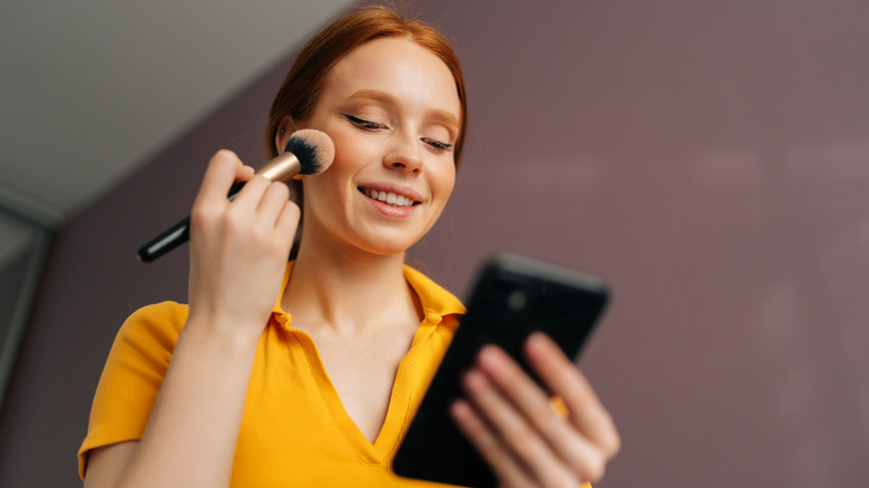 A woman applying blush