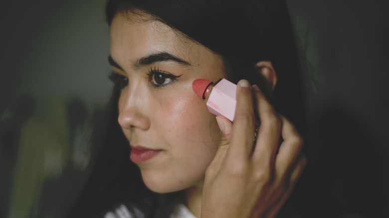 A woman applying liquid blush