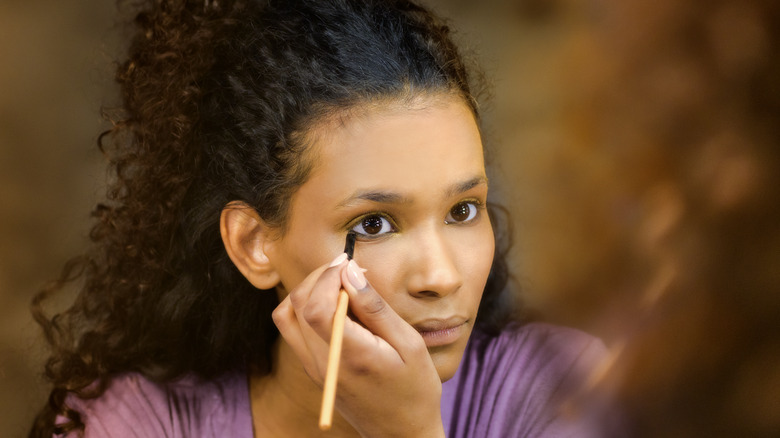 Black woman applying eyeliner