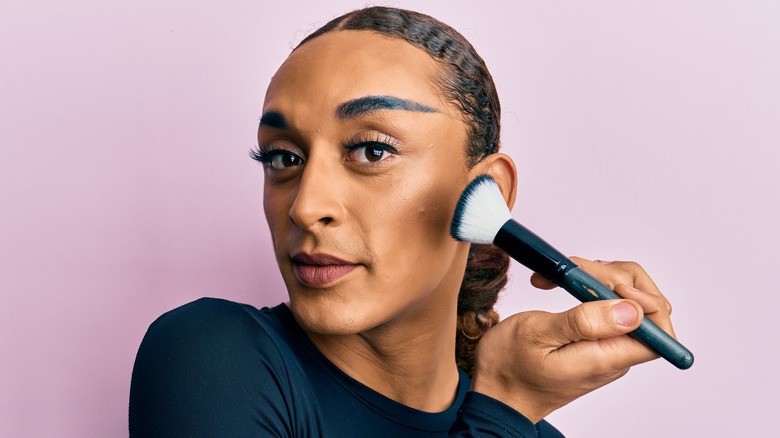 Person applying makeup to cheek
