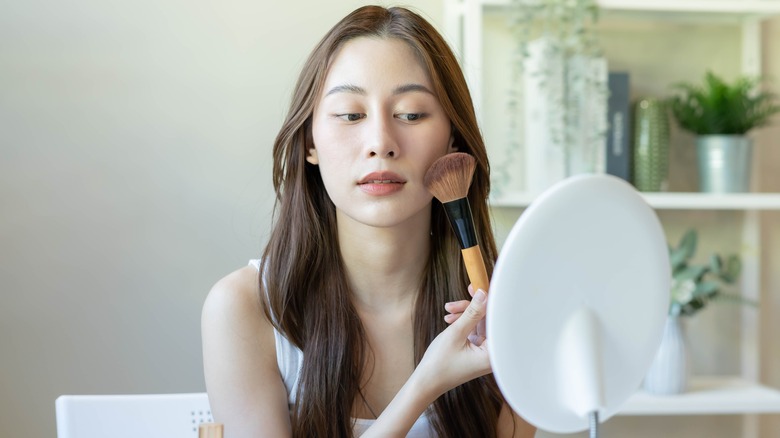 Woman applying blush with makeup brush