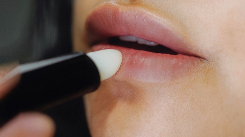 Woman putting on lip balm