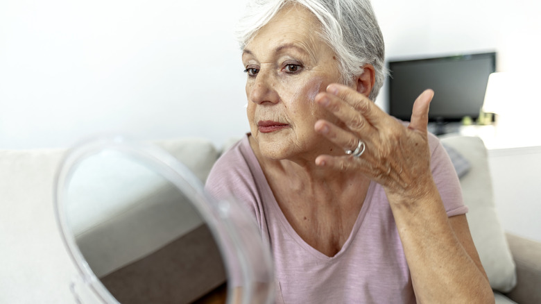 Woman applying makeup in the mirror