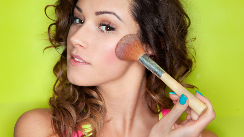 Woman applies bronzer with big brush 