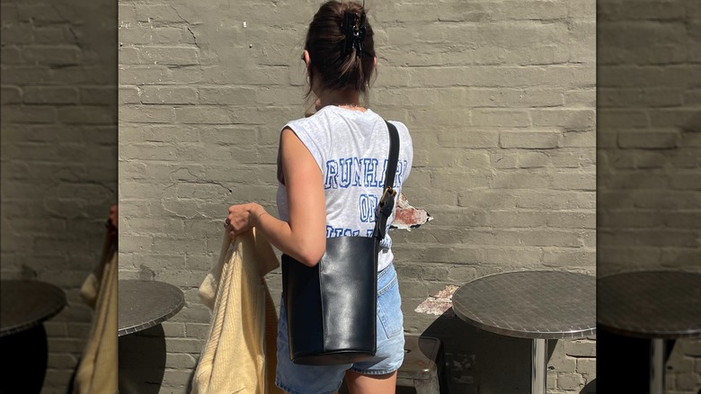 Woman holding crossbody leather bucket bag