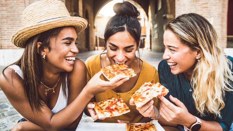 three friends eating pizza
