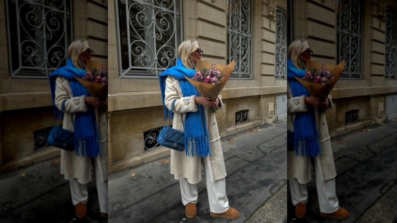 woman holding flowers with white coat and blue scarf