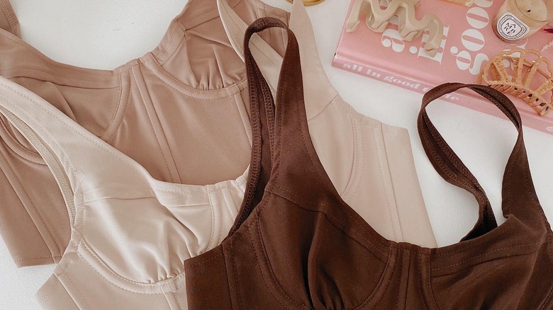 three corset tops in nude, beige, and brown laying on a table