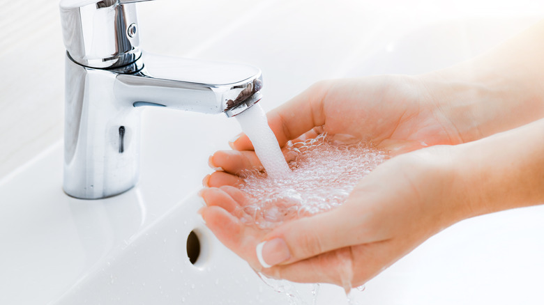 person washing hands with running tap water