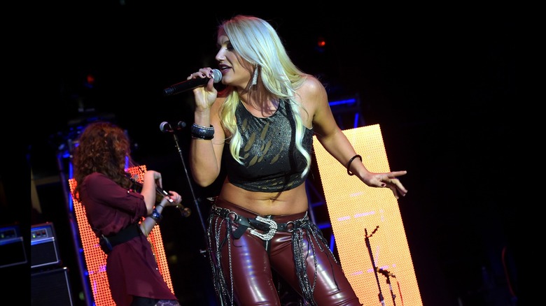 Brooke Hogan in red leather and a crop top while singing on stage.