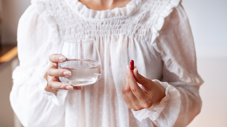 Woman holding water and vitamin