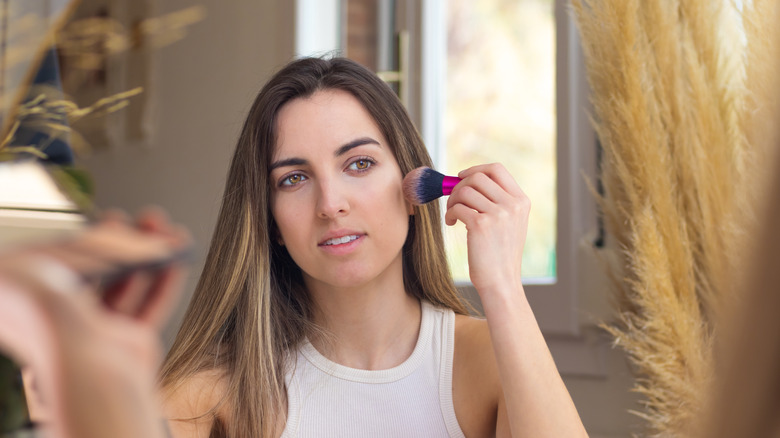 Woman using concealer brush