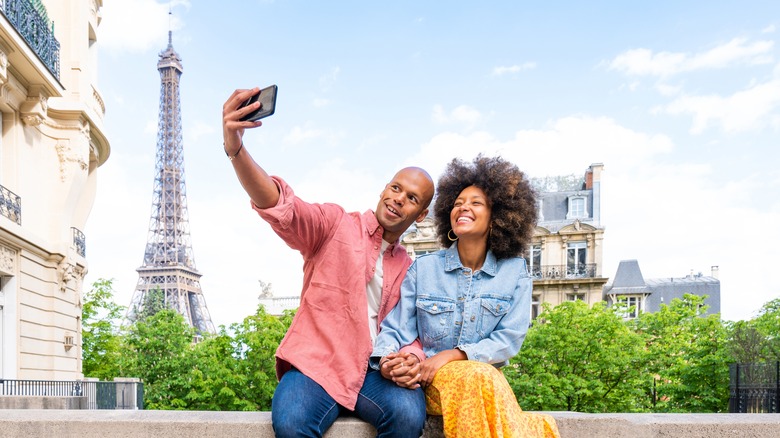 Couple taking selfie by Eiffel Tower