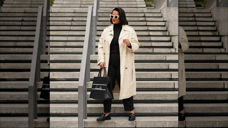 Woman wearing a trench coat over a black outfit.