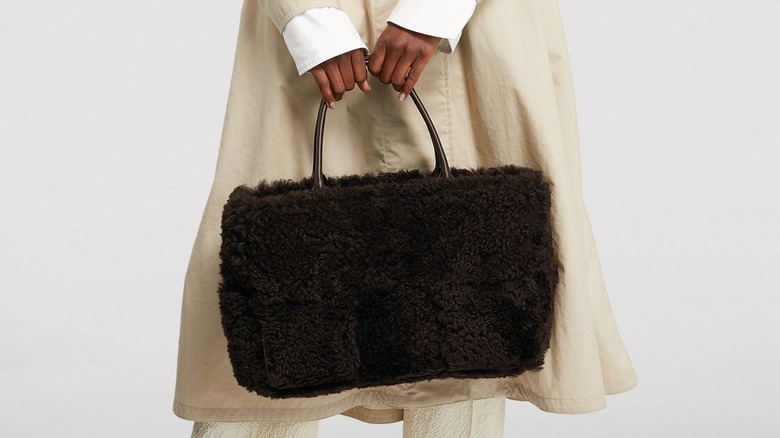 woman holding brown shearling tote